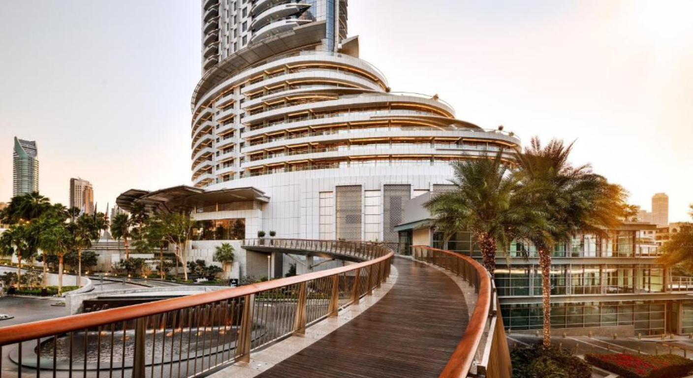 Exterior view of Address Downtown Dubai hotel with modern architecture and pedestrian walkway at sunset