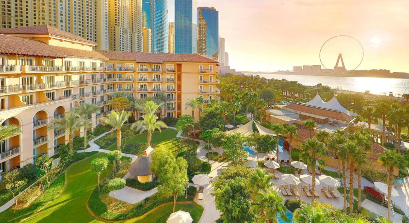 Aerial view of The Ritz-Carlton DIFC Dubai showcasing landscaped gardens, luxury resort buildings, and waterfront skyline at sunset