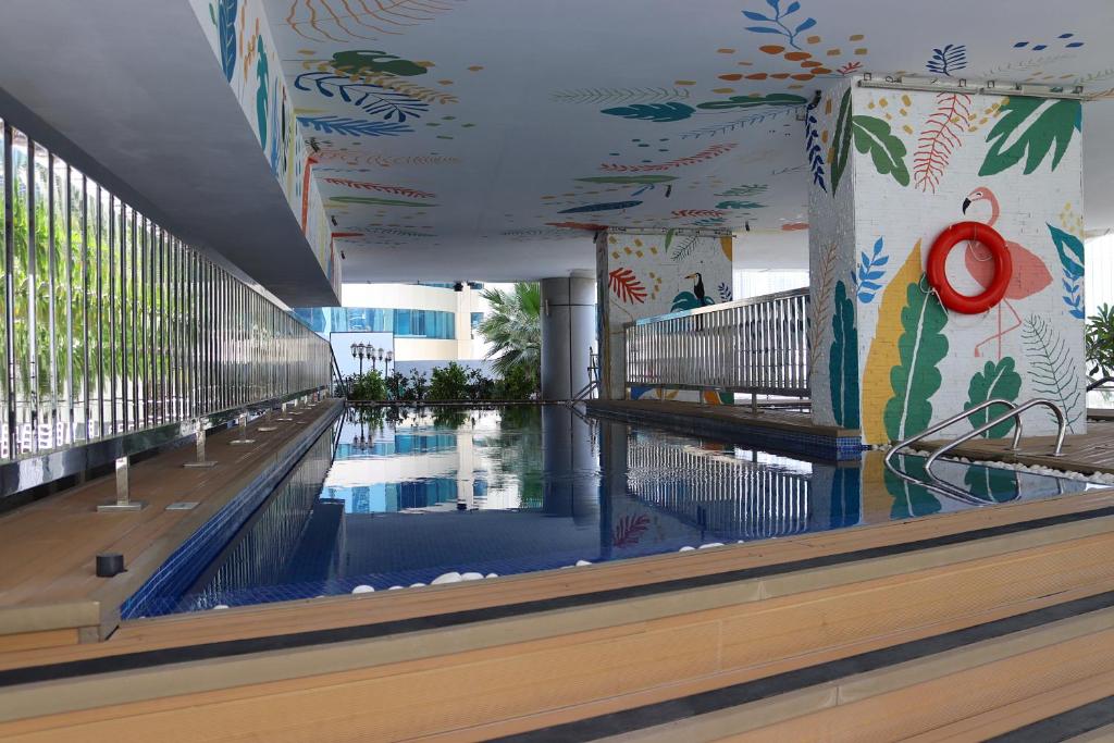 Indoor swimming pool at Park Regis Business Bay Hotel Dubai featuring modern design, colourful wall art, and city surroundings