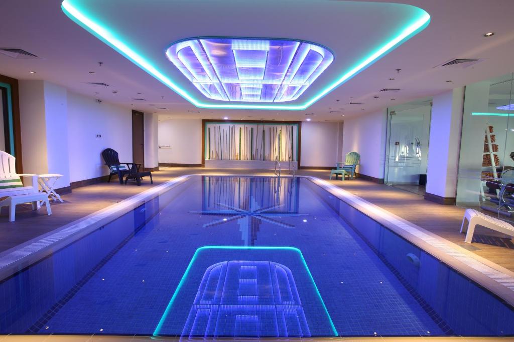 Indoor swimming pool at ibis Styles Dubai Jumeira with modern lighting, blue-tiled design, and relaxing seating area