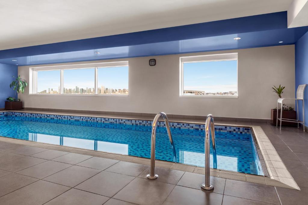 Indoor swimming pool at Ramada Plaza by Wyndham Dubai Deira with city skyline views through large windows
