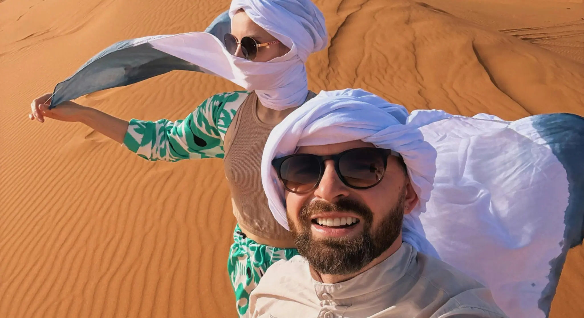 Couple enjoying Dubai desert adventure wearing traditional headscarves
