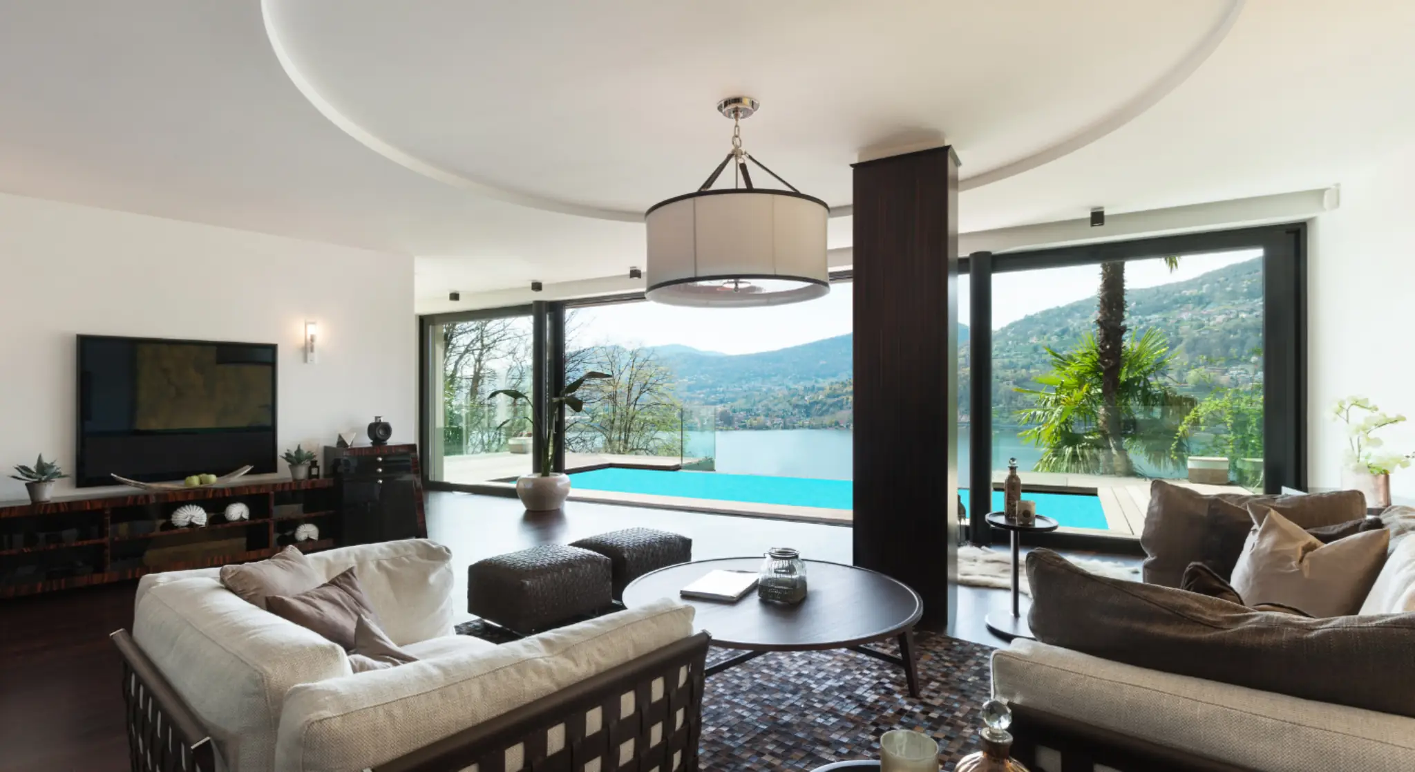 Modern luxury villa interior with pool view and large glass windows overlooking mountains 