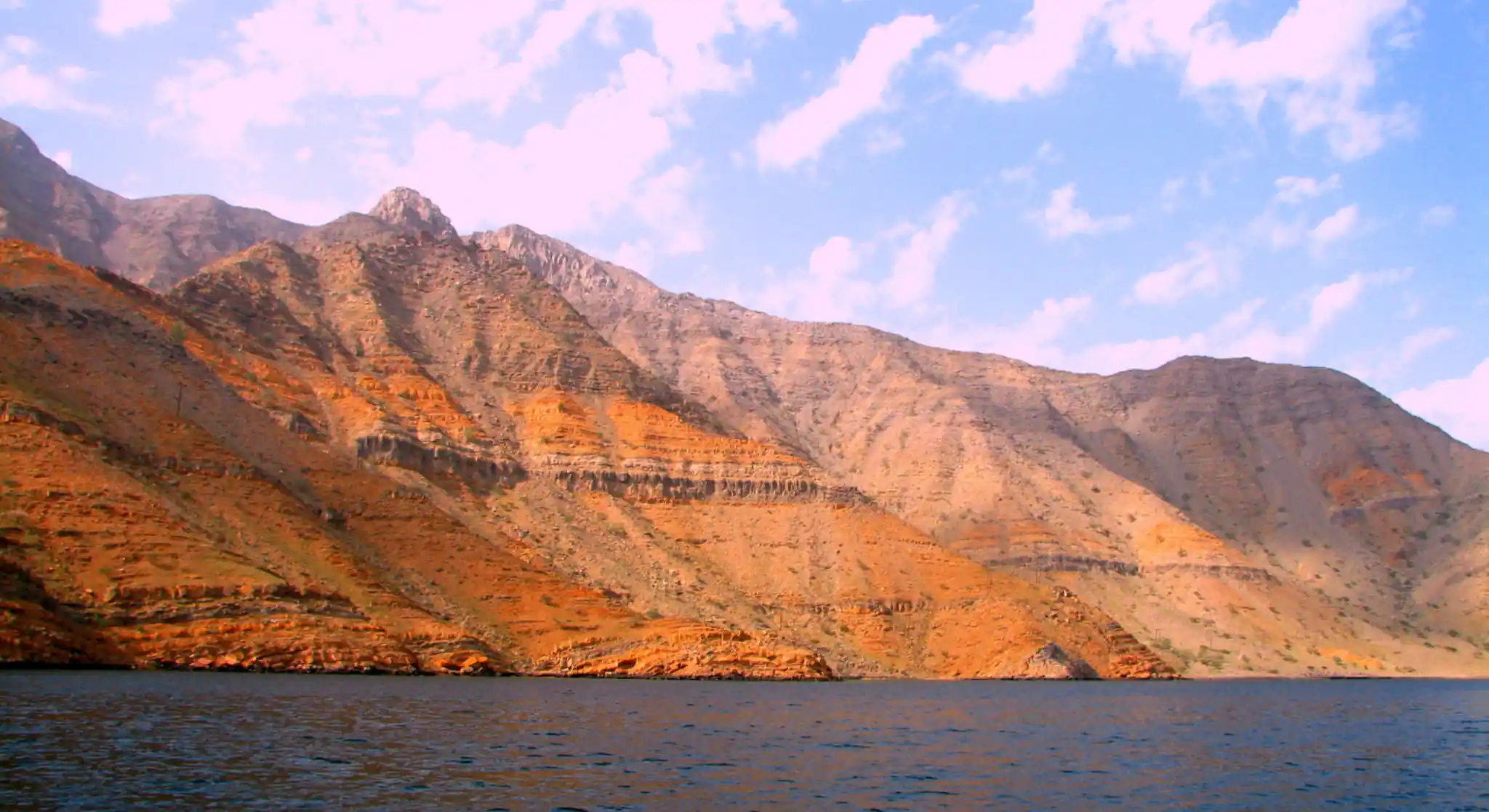 Dramatic mountain coastline in Musandam Oman viewed from dhow cruise on clear sea