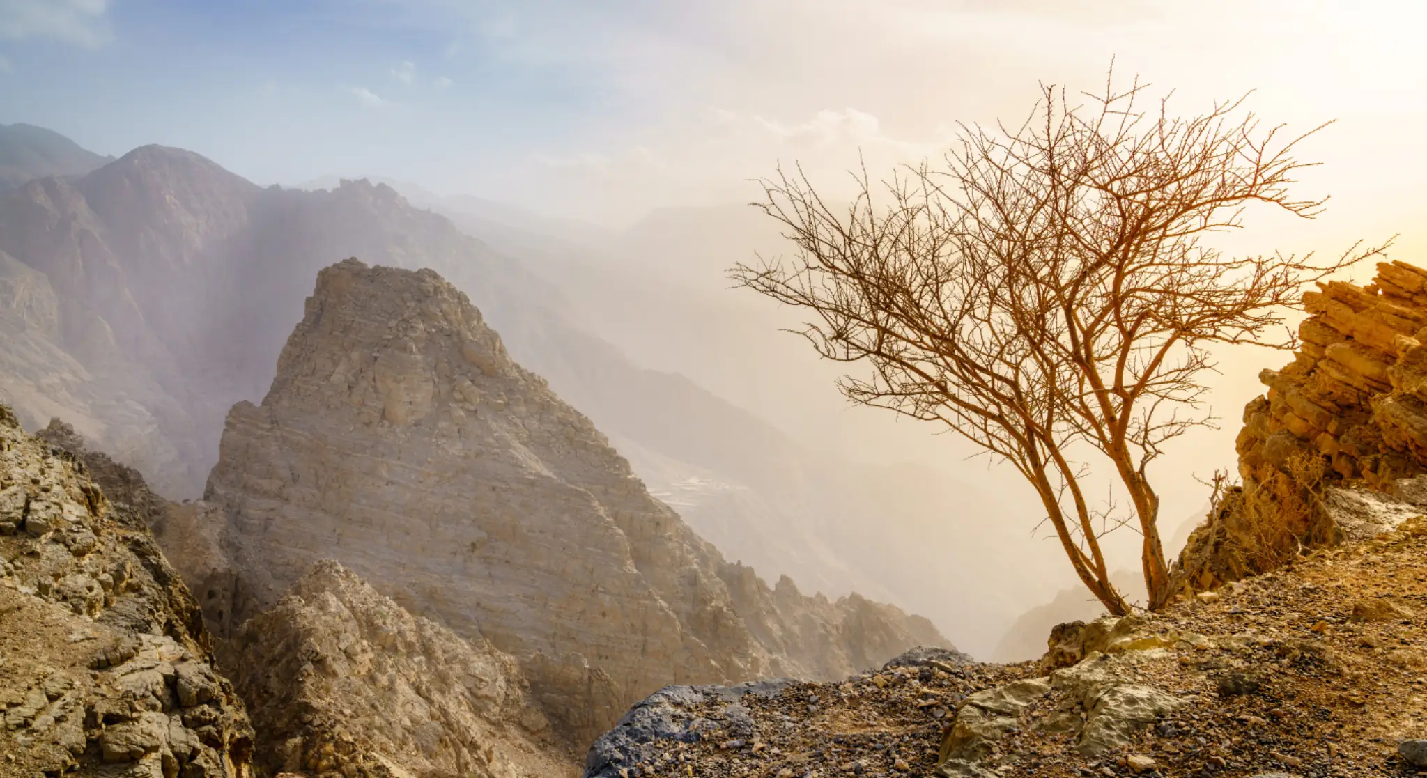 Scenic view of the Hajar Mountains in the UAE during golden hour with rocky desert landscape/