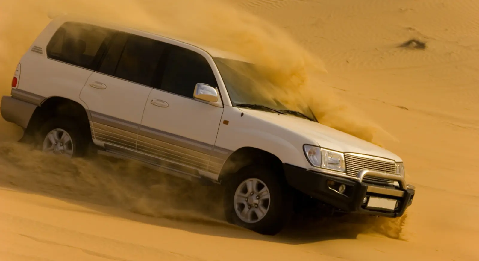 4x4 vehicle dune bashing during Dubai desert safari in golden sand dunes