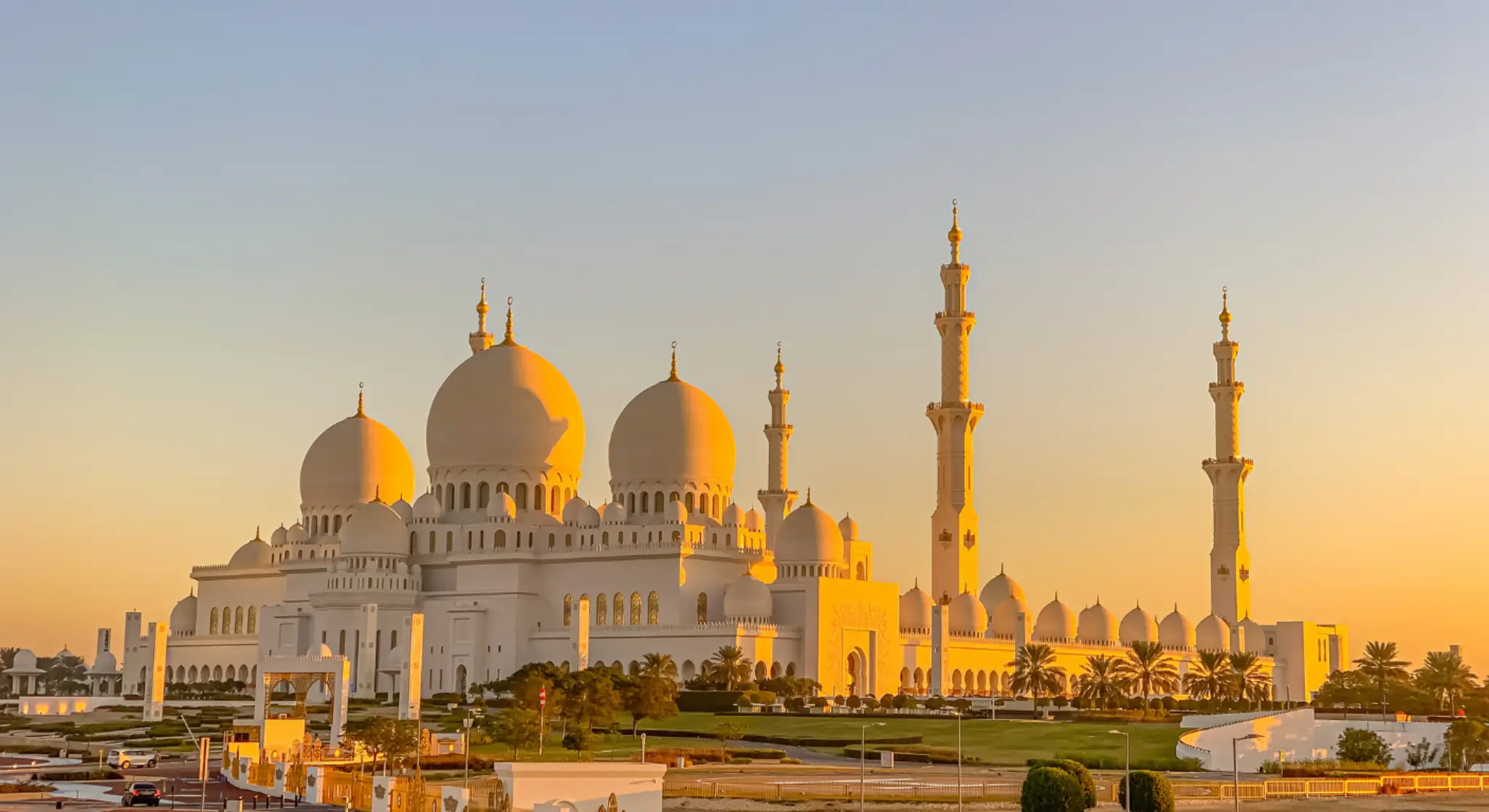 Sheikh Zayed Grand Mosque Abu Dhabi at sunset with glowing white domes and minarets