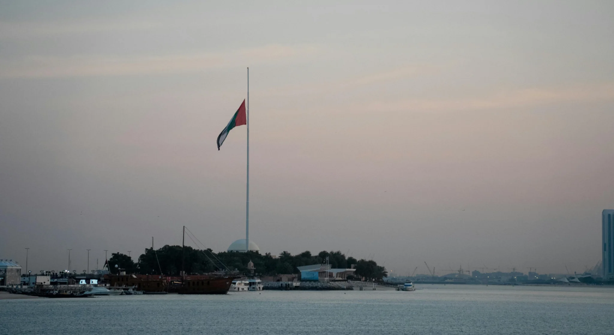 UAE flag at Abu Dhabi waterfront during evening skyline view
