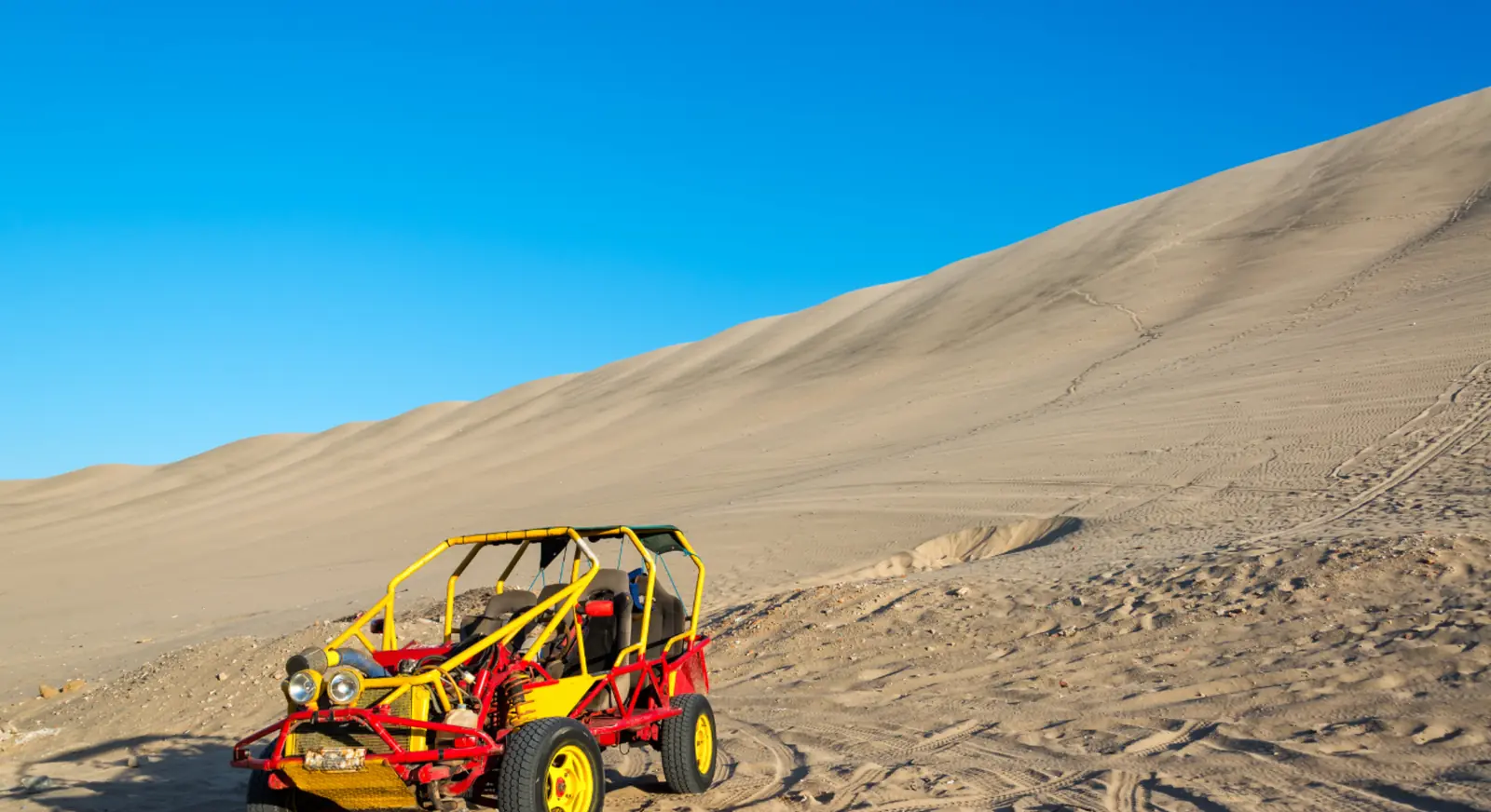 Red and yellow dune buggy on sandy desert slope