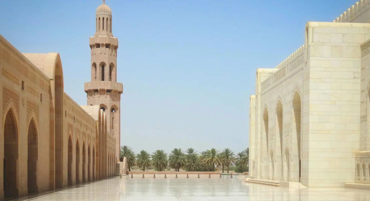 sheikh zayed grand mosque courtyard with minaret and palm trees in abu dhabi