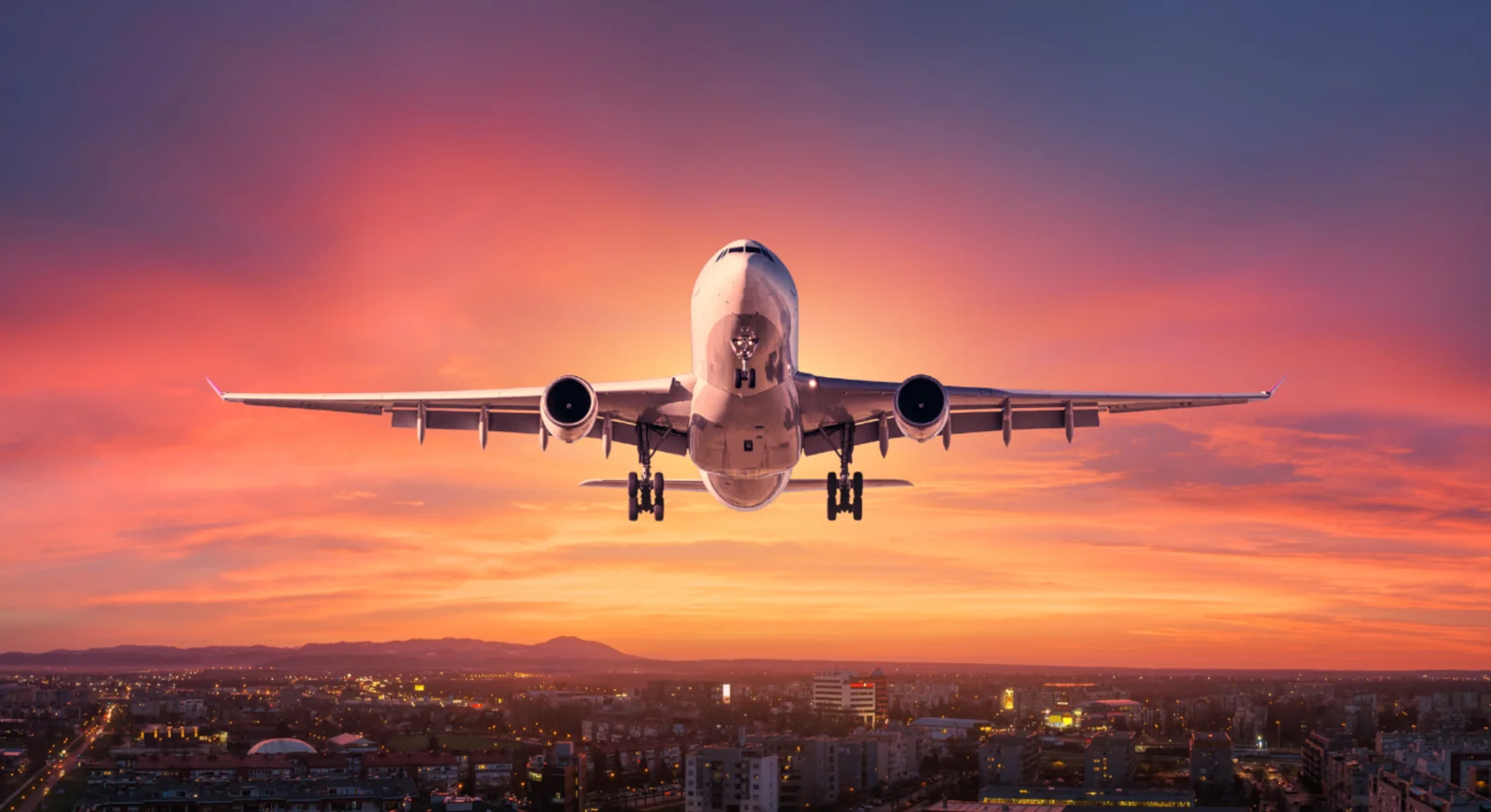 Airplane landing over city skyline during sunset representing international travel to the UAE