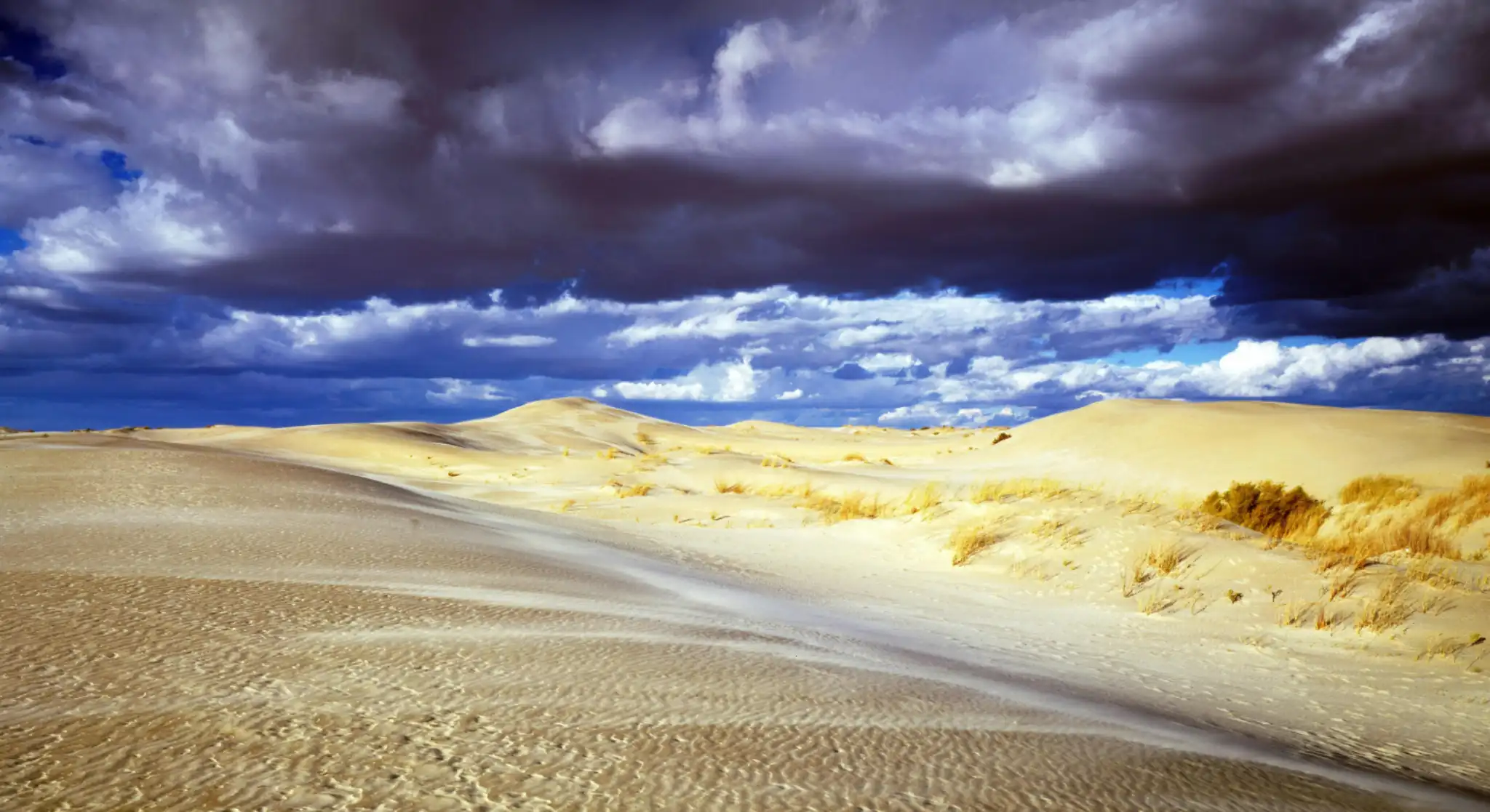 dramatic clouds over golden desert sand dunes landscape