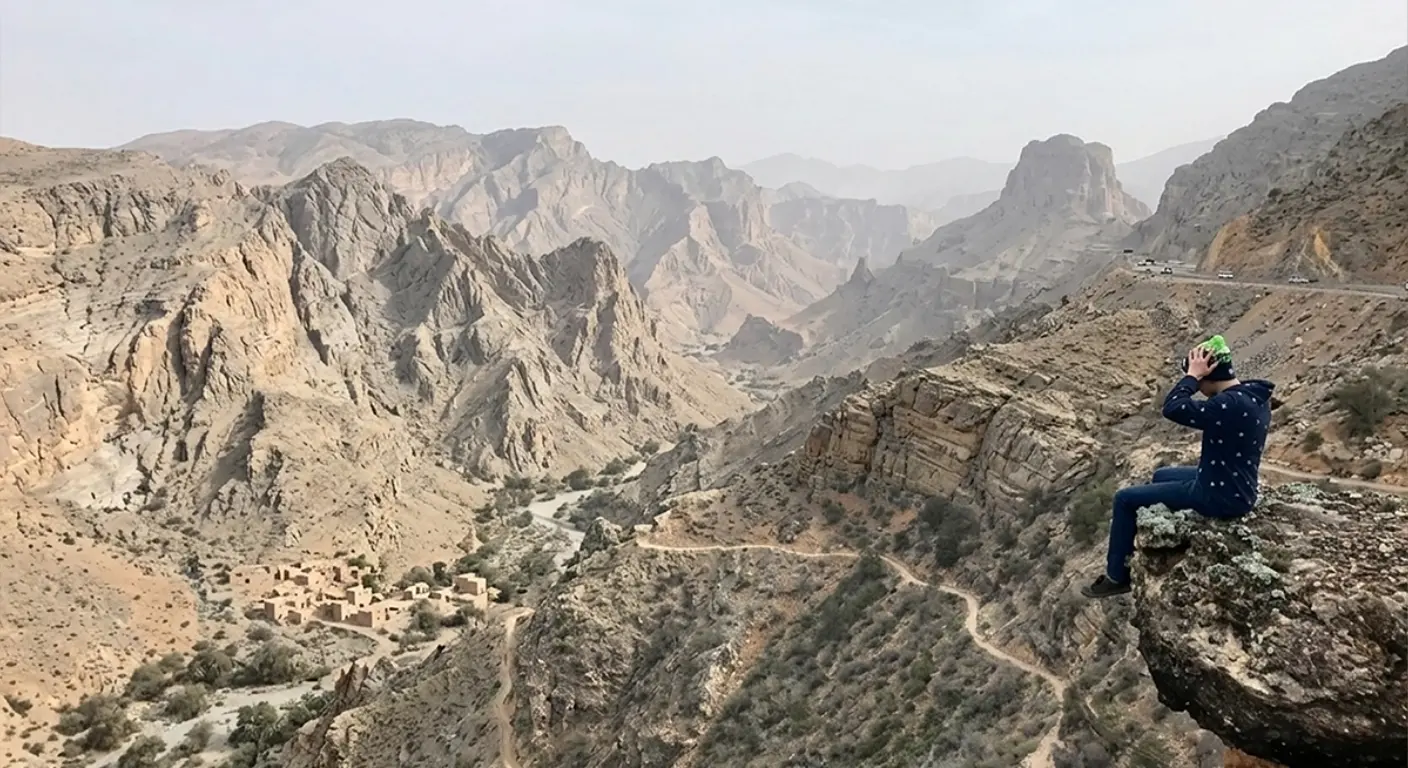 Scenic mountain view at Jebel Jais Ras Al Khaimah with traveller sitting on cliff