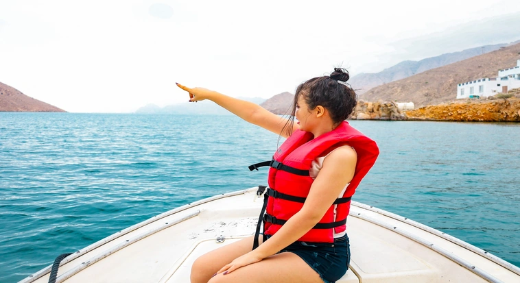Visitor wearing a life jacket on a boat exploring the Musandam fjords in Oman