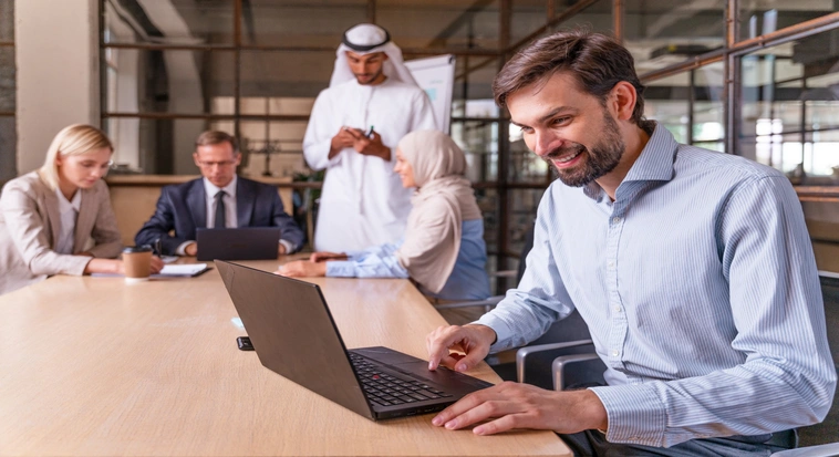 Professional working on a laptop with colleagues during UAE employment visa and residency processing