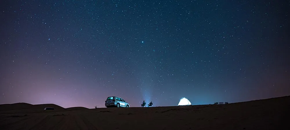 Visitor in light layers and a scarf on a Liwa dune in winter