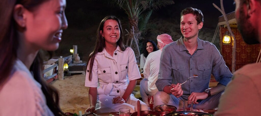 Guests enjoying dinner at a Dubai desert safari camp in the evening