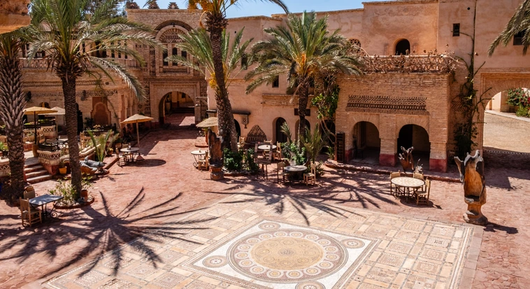 Traditional Moroccan riad courtyard with palm trees and geometric tilework