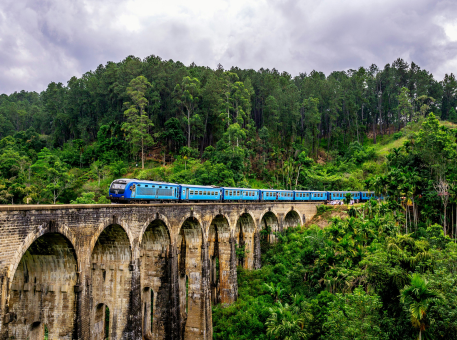Blue train crossing the Nine Arch Bridge in Ella, photographed by Jude Abraham during a hill-country route inspection for Arabiers