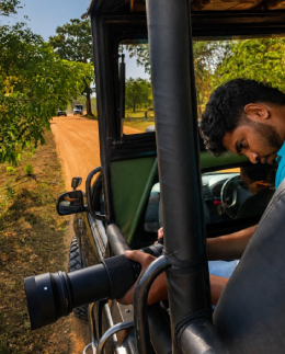 Jude Abraham photographing from a safari jeep during a personal route inspection at Yala National Park, Sri Lanka, checking wildlife sightings and tracks before adding the safari to guest itineraries