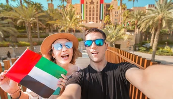 Couple enjoying a Dubai holiday with a UAE flag during a honeymoon package from Sri Lanka